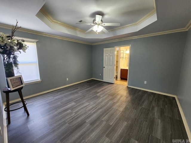 interior space with a tray ceiling, baseboards, and dark wood-type flooring