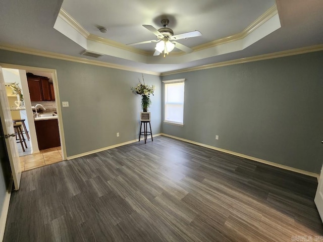 unfurnished room with visible vents, dark wood finished floors, a tray ceiling, ceiling fan, and a sink