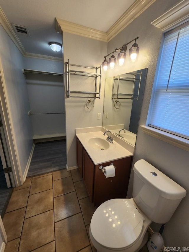 half bath featuring tile patterned flooring, visible vents, toilet, ornamental molding, and vanity