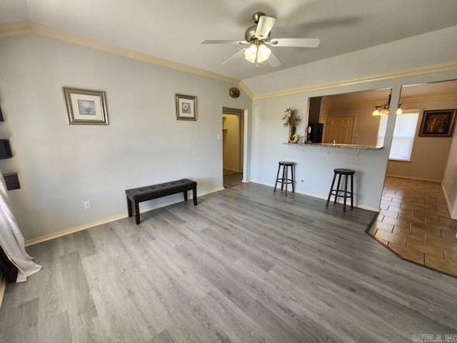 unfurnished living room featuring wood finished floors, ceiling fan, ornamental molding, and vaulted ceiling