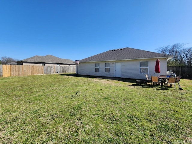 rear view of house featuring a yard and a fenced backyard