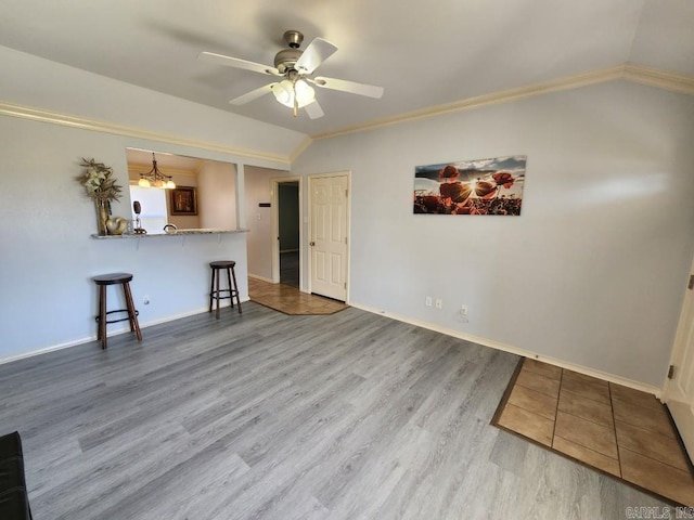 unfurnished living room with baseboards, lofted ceiling, ornamental molding, ceiling fan with notable chandelier, and wood finished floors