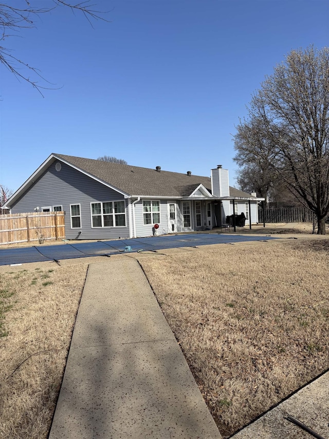 rear view of property with a chimney and fence