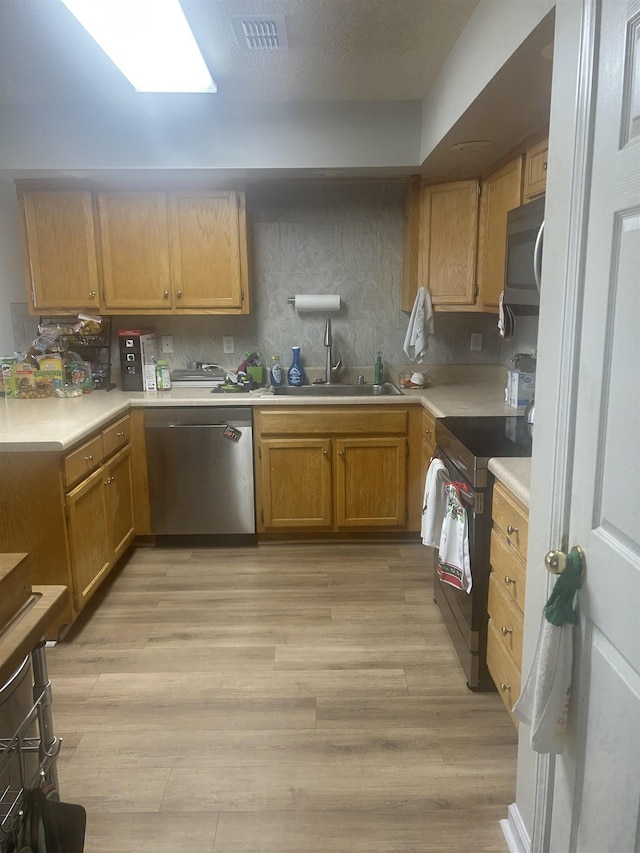 kitchen with light wood finished floors, visible vents, light countertops, stainless steel appliances, and a sink