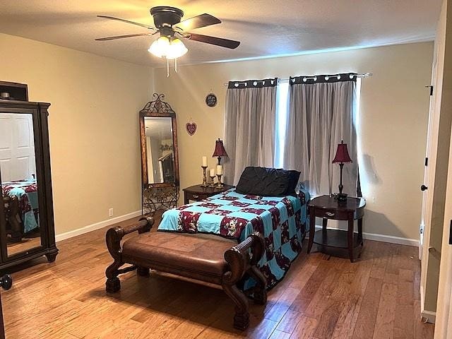 bedroom featuring baseboards, a ceiling fan, and hardwood / wood-style flooring