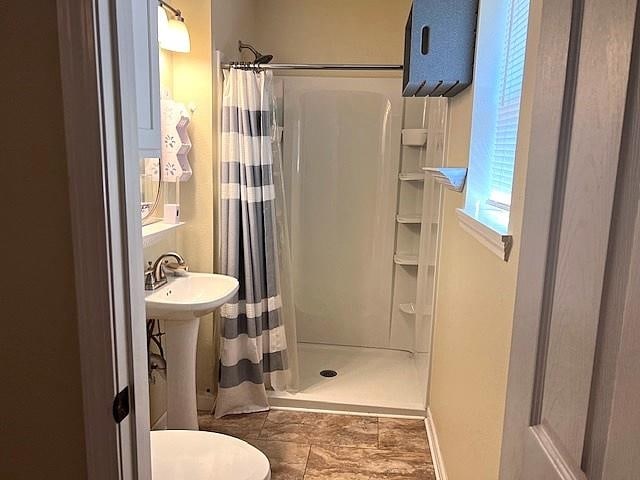 full bathroom with a sink, baseboards, toilet, and a stall shower