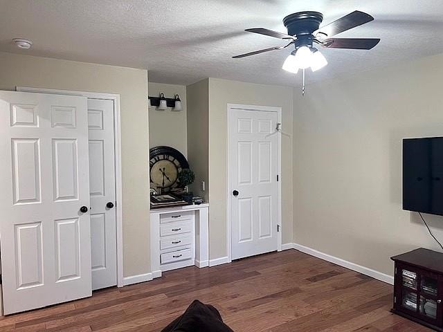 bedroom with ceiling fan, baseboards, a textured ceiling, and dark wood finished floors