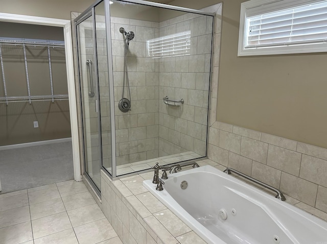 full bath featuring tile patterned floors, a spacious closet, a stall shower, and a whirlpool tub