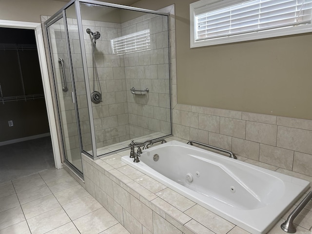 bathroom with tile patterned flooring, a tub with jets, a stall shower, and a walk in closet