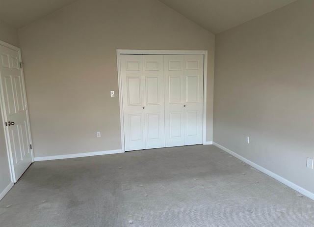 unfurnished bedroom with a closet, carpet flooring, baseboards, and lofted ceiling