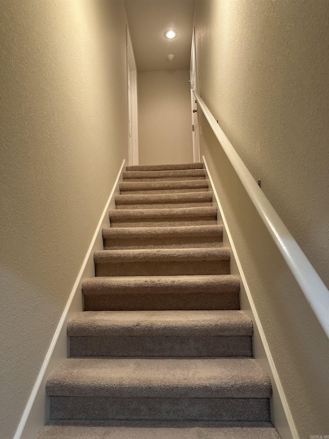 stairs featuring recessed lighting and a textured wall