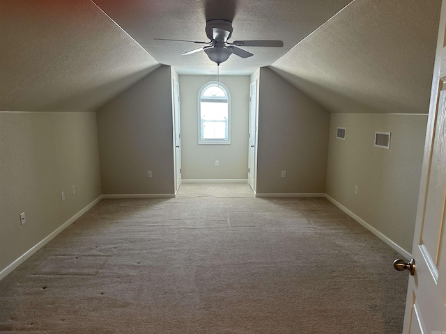 additional living space featuring light carpet, baseboards, a textured ceiling, and ceiling fan