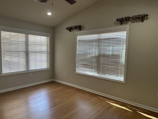 empty room with vaulted ceiling, wood finished floors, a ceiling fan, and baseboards