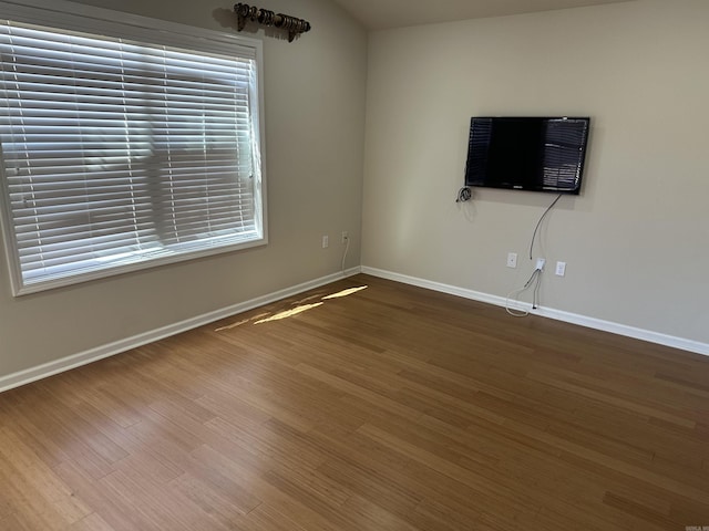 unfurnished living room featuring wood finished floors and baseboards