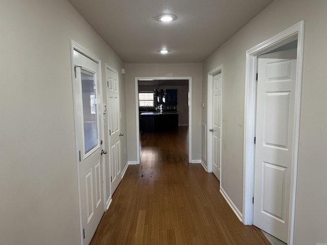 corridor featuring baseboards and dark wood-style floors