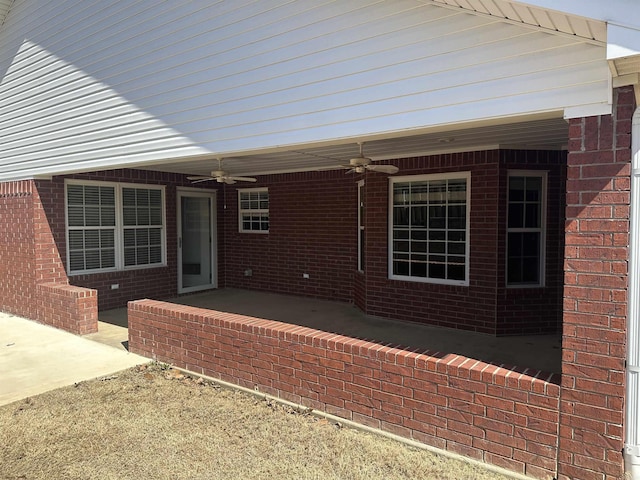 exterior space with a patio, a ceiling fan, and brick siding