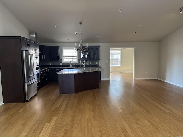 kitchen featuring light wood finished floors, a center island, a sink, open floor plan, and a chandelier