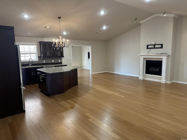 kitchen featuring a kitchen island, a chandelier, lofted ceiling, freestanding refrigerator, and light wood-style floors