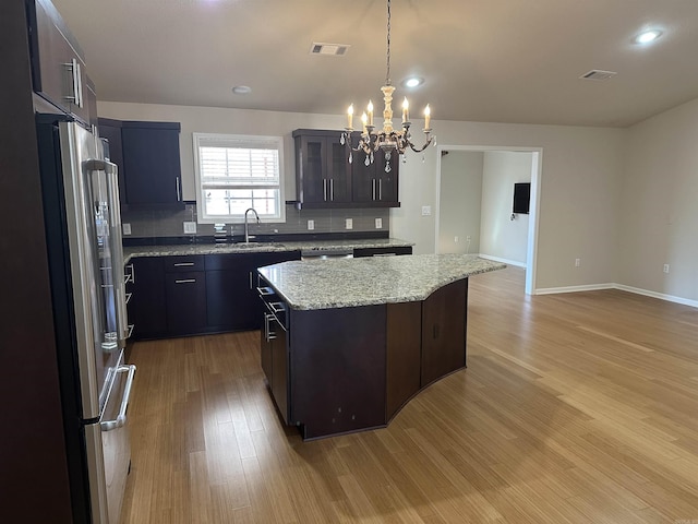 kitchen featuring visible vents, high end fridge, a sink, a notable chandelier, and light wood-type flooring