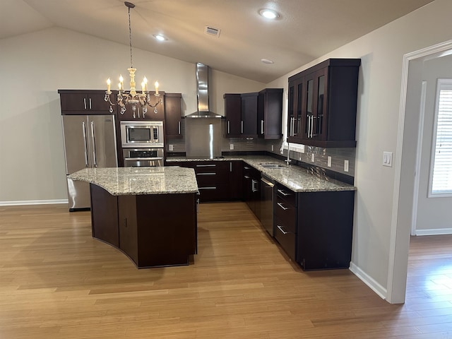 kitchen with visible vents, appliances with stainless steel finishes, a notable chandelier, wall chimney exhaust hood, and a sink