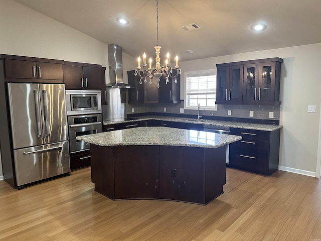 kitchen featuring visible vents, light wood-style floors, appliances with stainless steel finishes, wall chimney range hood, and a chandelier