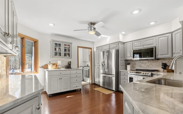 kitchen with a ceiling fan, light stone countertops, dark wood-style flooring, gray cabinetry, and appliances with stainless steel finishes