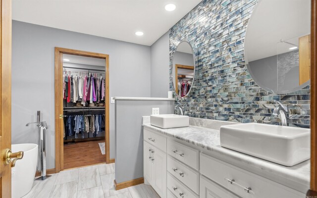 full bath with a walk in closet, tasteful backsplash, and a sink