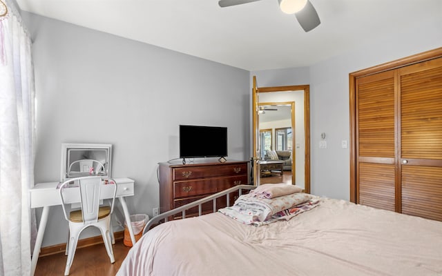 bedroom with a closet, ceiling fan, baseboards, and wood finished floors