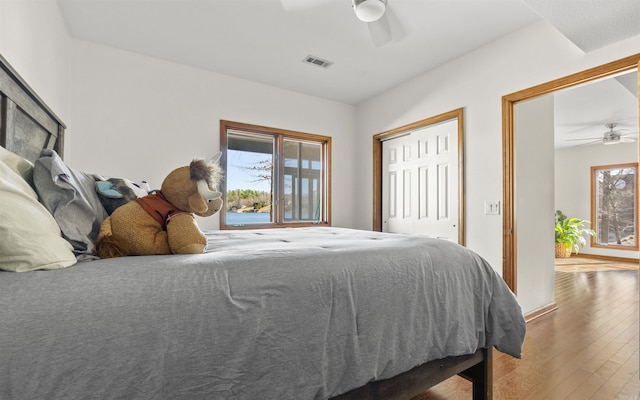 bedroom with a closet, visible vents, a ceiling fan, and hardwood / wood-style flooring