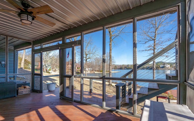 unfurnished sunroom featuring a ceiling fan and a water view