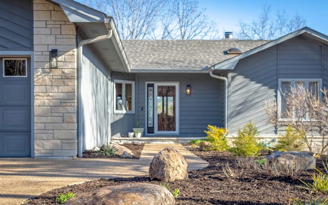 property entrance with stone siding, a garage, and roof with shingles