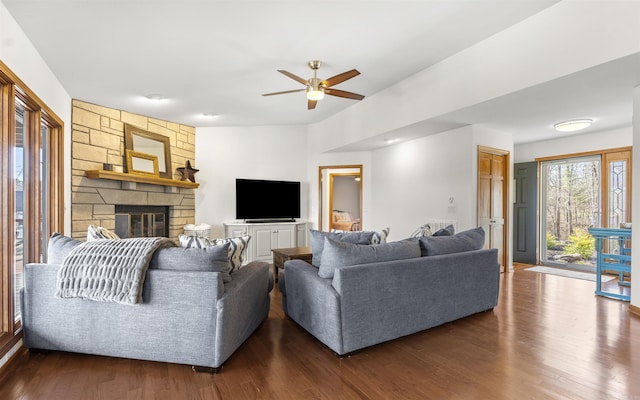 living area with a fireplace, dark wood-type flooring, and a ceiling fan