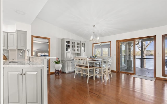 dining area featuring a wealth of natural light, dark wood-type flooring, a chandelier, and vaulted ceiling