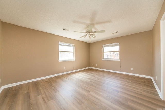 spare room featuring baseboards, wood finished floors, visible vents, and ceiling fan