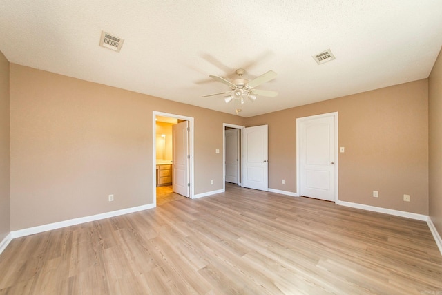 unfurnished bedroom with ensuite bath, baseboards, visible vents, and light wood finished floors