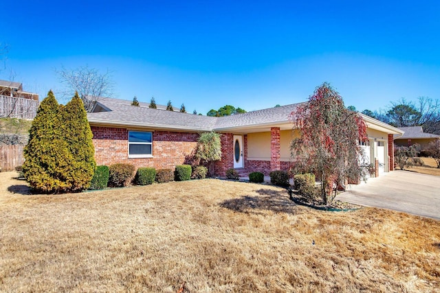 ranch-style house featuring brick siding, an attached garage, concrete driveway, and a front yard