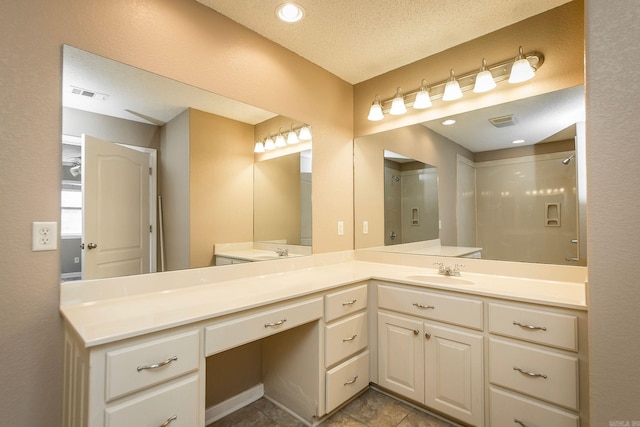 full bathroom featuring visible vents, a textured ceiling, walk in shower, and vanity