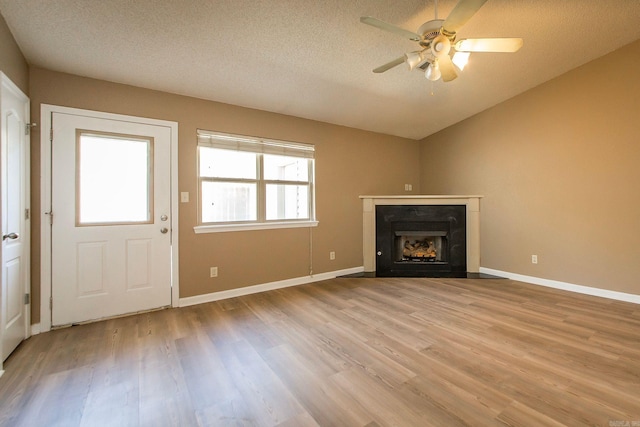 unfurnished living room featuring lofted ceiling, a textured ceiling, ceiling fan, and light wood finished floors