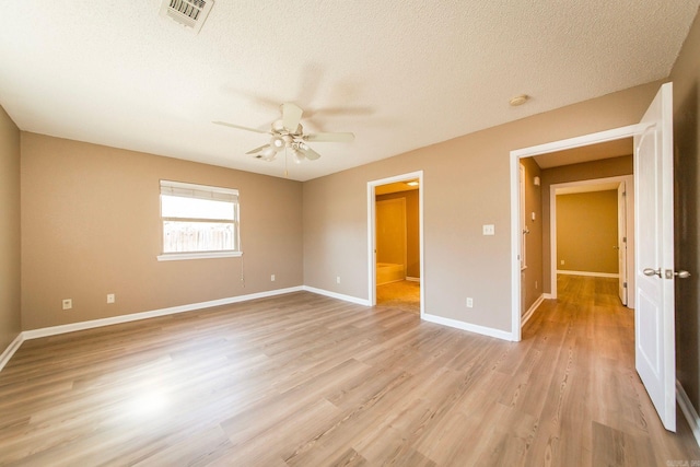 unfurnished bedroom with light wood-type flooring, visible vents, baseboards, and a textured ceiling