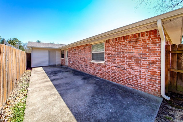 exterior space with a patio, fence, and brick siding