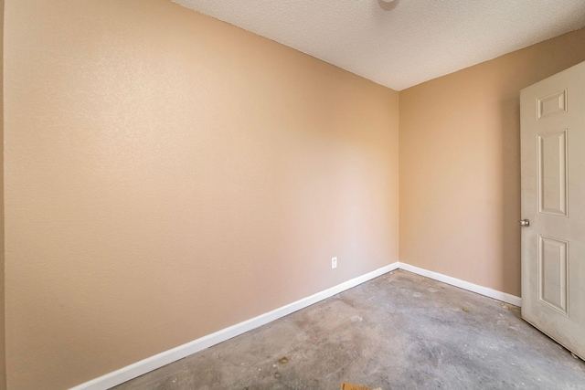 empty room with baseboards, a textured ceiling, and unfinished concrete floors