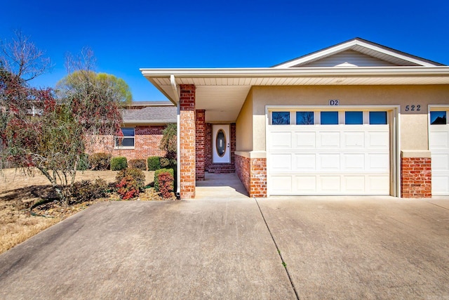 single story home featuring brick siding, stucco siding, an attached garage, and concrete driveway