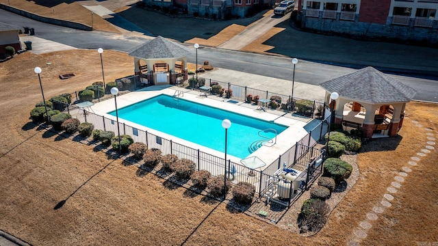 community pool with a gazebo, fence, and a patio area