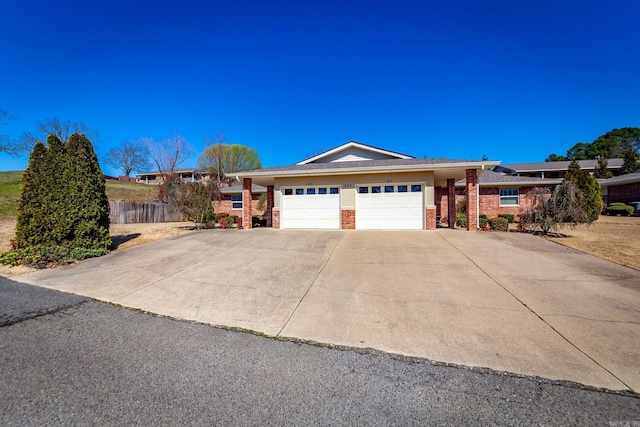 single story home featuring brick siding, concrete driveway, a garage, and fence