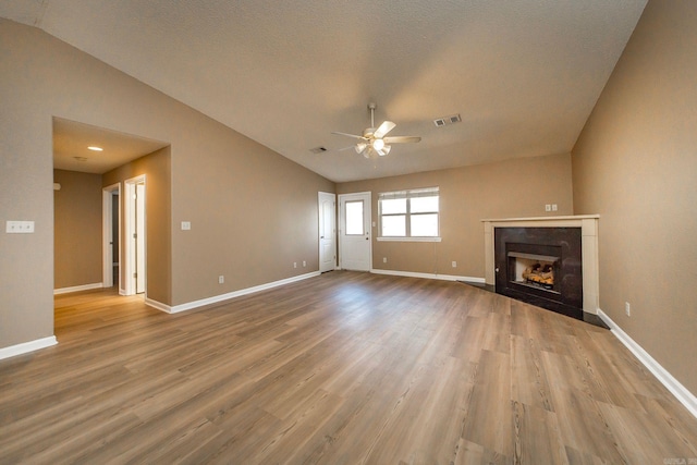 unfurnished living room featuring vaulted ceiling, visible vents, a ceiling fan, and wood finished floors