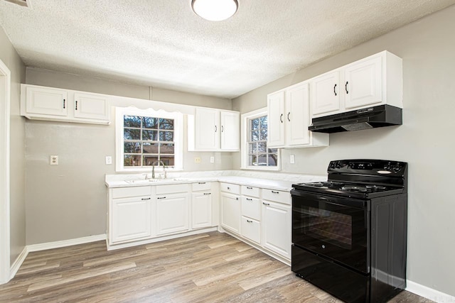 kitchen with a sink, black range with electric cooktop, light wood-style floors, under cabinet range hood, and white cabinetry