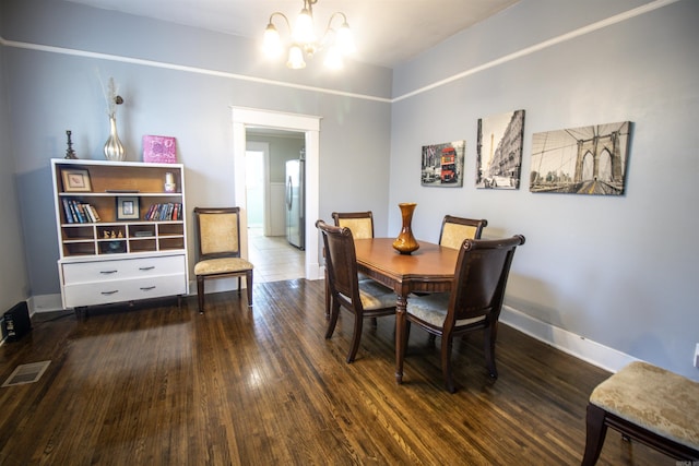 dining space featuring a notable chandelier, wood finished floors, visible vents, and baseboards