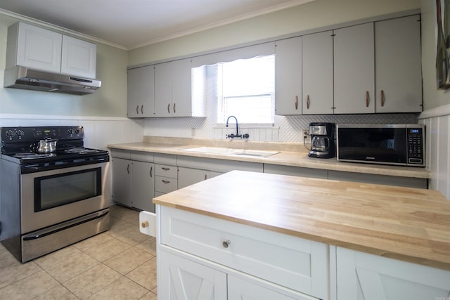 kitchen featuring electric stove, under cabinet range hood, a sink, crown molding, and wooden counters