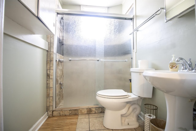 bathroom featuring a shower stall, toilet, and a sink