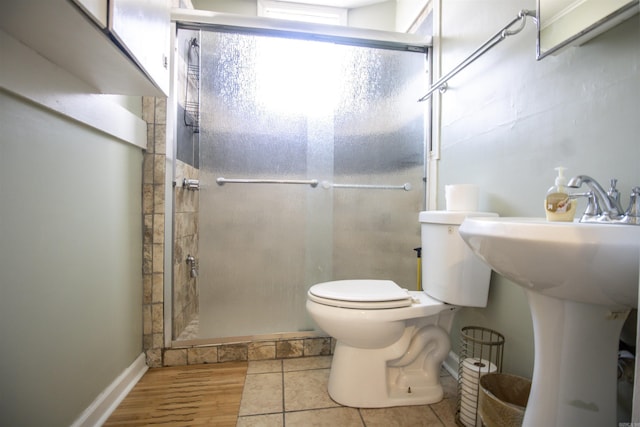 bathroom featuring a sink, a stall shower, toilet, and wood finished floors